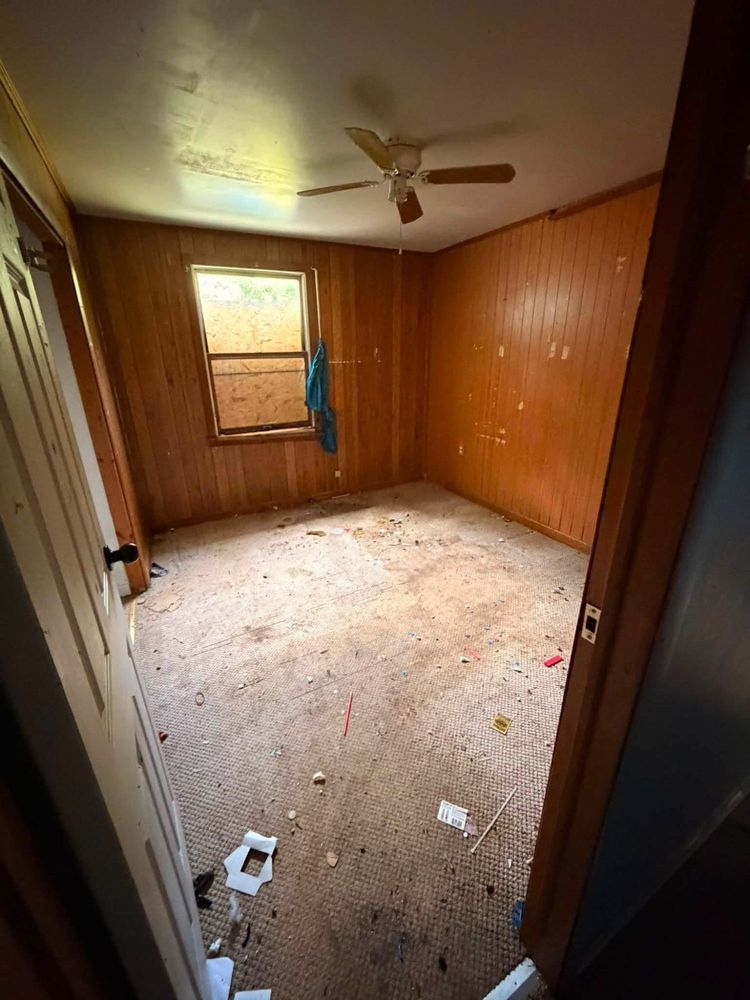 The same wood-paneled Elkton bedroom emptied to the walls, with bare carpet and the ceiling fan above