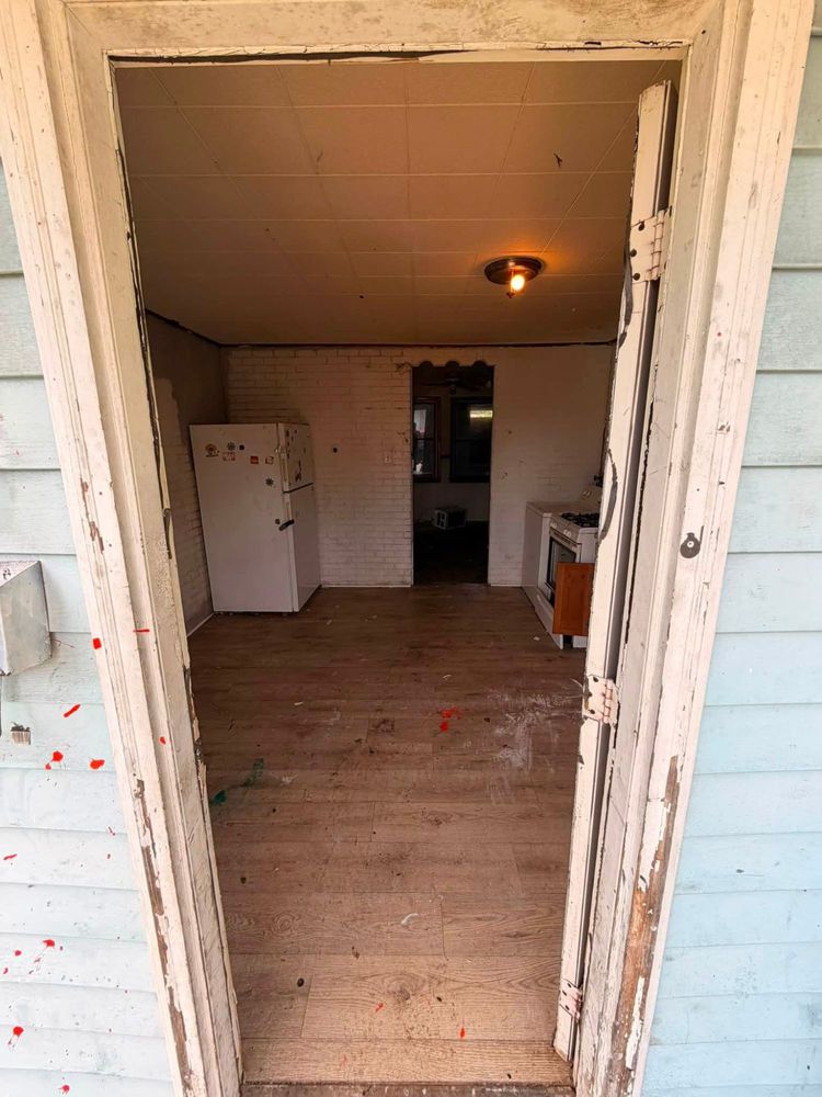 The same Elkton kitchen cleared to bare floor after the cleanout, with only the refrigerator left in place