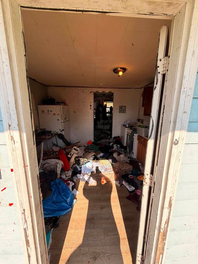 Kitchen of an Elkton, Maryland hoarder house seen from the front door, floor covered wall to wall in clothing, bedding and household debris